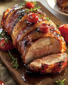 sliced pork with tomatoes and herbs on a cutting board