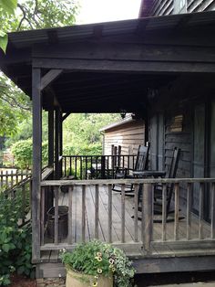 a porch with rocking chairs on it next to a house