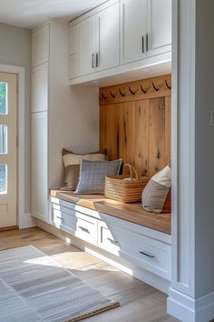 a wooden bench sitting in the middle of a room next to white cabinets and drawers