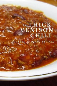 thick venison chili in a white bowl on a wooden table with the words, thick venison chili country at heart recipes