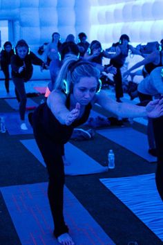 a group of people doing yoga in a room with blue lights on the walls and floor