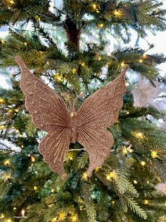 a christmas tree with a brown butterfly ornament hanging from it's side