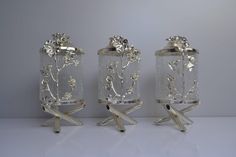 three glass vases with flowers and leaves on them