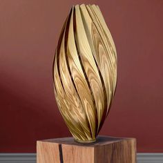 a wooden sculpture sitting on top of a wooden block next to a red painted wall