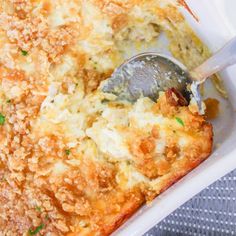 a casserole dish filled with meat and cheese being spooned into the casserole