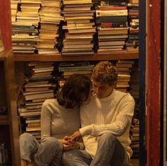 two people sitting in front of a book shelf full of books