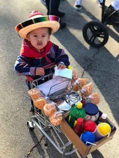 a small child in a straw hat is pushing a cart full of food and condiments