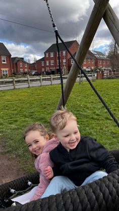 two young children sitting in a rope swing