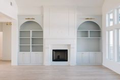 an empty living room with built - in bookshelves and fireplace