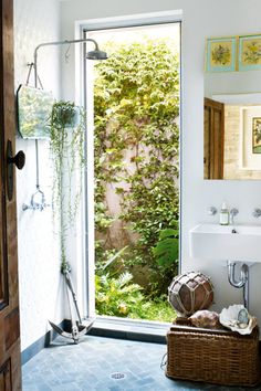 a bathroom with an open door leading to a lush green garden behind the sink and toilet