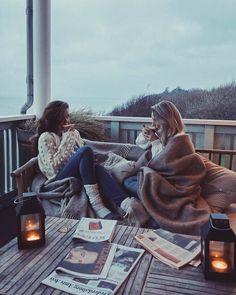 two women sitting on a deck talking to each other