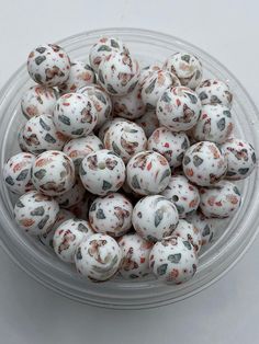 a bowl filled with lots of white and red speckled balls on top of a table