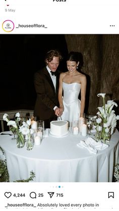 a man and woman cutting a cake on top of a table with candles in front of them