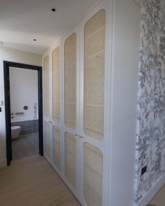 a bathroom with white cabinets and wallpaper on the walls, along with a toilet