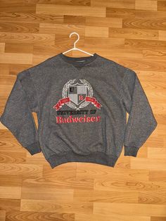 Vintage Budweiser Sweatshirt  - Rare  - 80's vintage  - University of Budweiser logo  - College crest graphic  - Licensed Anheuser  Size: Medium  23" pit to pit  26" shoulder to waist  Good vintage condition small ripping near B no holes  No stains Vintage Letter Print Sweatshirt For Fan Gear, Crew Neck Top With Embroidered Logo For Fans, Vintage Logo Print T-shirt, Vintage Letter Print Sweatshirt For Game Day, Crew Neck Tops With Embroidered Logo For Sports Events, Vintage Graphic Print Sweatshirt For Fan Gear, Vintage Graphic Print Sweatshirt For Fans, Vintage Fan Merchandise Graphic Sweatshirt, Vintage Graphic Print Sweatshirt For Fan Merchandise