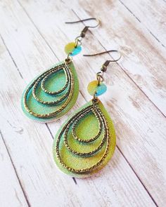 two pairs of green earrings on top of a wooden table