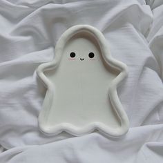 a white plate with a little ghost on it's side, sitting on a bed