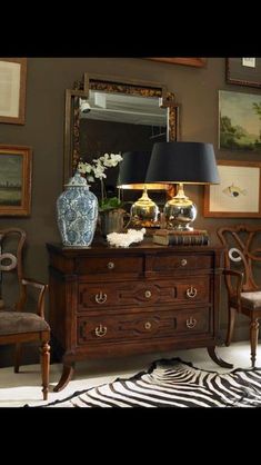 a living room with zebra print rugs and antique furniture in the foreground, framed pictures on the wall