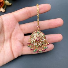 This magnificent mang teeka / tikka is designed in 22k gold with an intricately placed ruby, emerald and pearl design. Its chain measures 4 inches in length with a detachable hook at the end. It boasts an impressive total weight of 8.39 gms, 0.85 gms of which is concentrated in the ruby-emerald beads. This timeless piece is the perfect accessory for special occasions and can be passed down for generations as a treasured heirloom. The blend of precious gems and gold make it a stunning piece sure 22k Gold Tikka With Intricate Design, Yellow Gold Temple Jewelry Tikka For Festive Occasions, Festive Yellow Gold Tikka With Tilla, Festive Yellow Gold Tilla Tikka, 22k Gold Temple Jewelry Tikka With Tilla, 22k Gold Temple Jewelry Tikka, 22k Gold Tikka For Diwali, 22k Gold Tikka For Diwali Festival, Festive 22k Gold Tikka With Tilla Detailing