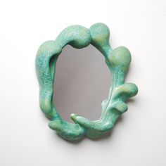 a green frog shaped mirror sitting on top of a white wall