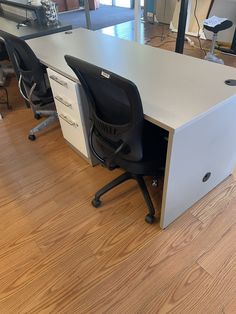 an office desk with two black chairs next to it on a hard wood flooring area