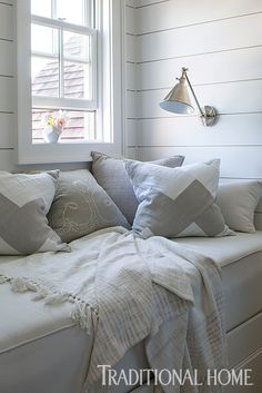 a bed with white comforters and pillows on top of it next to a window