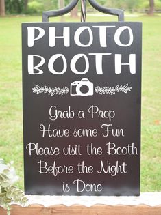 a sign that says photo booth on the side of a wooden table in front of grass