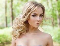 a woman with blonde hair wearing a strapless dress in the woods looking at the camera