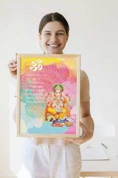 a woman holding up a framed poster with an image of the hindu god