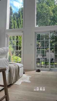 a living room filled with lots of windows next to a wooden chair and table in front of it