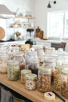 jars filled with food sitting on top of a wooden table next to a counter in a kitchen