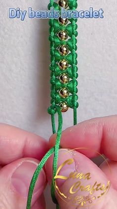 a hand holding a green string with gold beads on it's end and a beaded bracelet in the middle