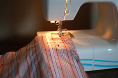 the sewing machine is on top of the striped material that has been stitched together