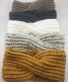 four different colors of knitted headbands laying on top of eachother