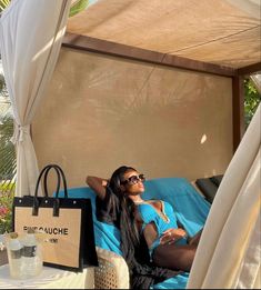 a woman laying on top of a bed next to a brown bag and some bottles