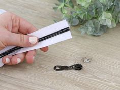 a person holding a pair of black and white zippers on top of a wooden table