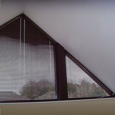 the corner of a room with two windows covered in blinds