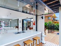 an open concept kitchen and living room with wood flooring, white countertops and stainless steel railings