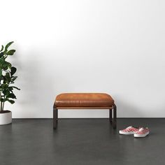 a pair of slippers sitting on top of a wooden bench next to a potted plant