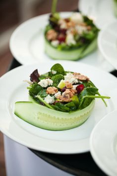 three white plates topped with cucumbers and other food on top of a table