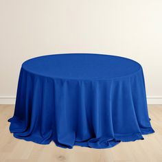 a round table with a blue cloth draped over it on a hard wood flooring area