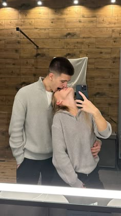 a man and woman taking a selfie in front of a mirror with their cell phone