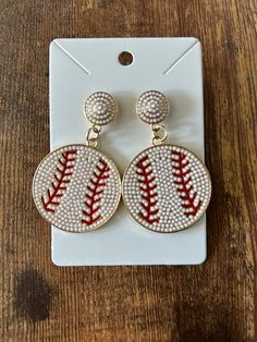 a pair of baseball earrings on top of a wooden table