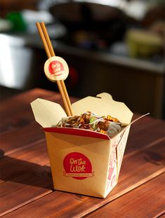 a take out box with chopsticks sticking out of it