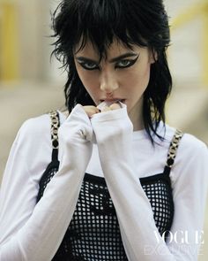 a woman with black hair and white shirt holding her hands to her face while standing on the street