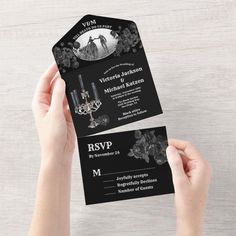 a person holding up a black and white wedding card