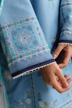 a close up of a person's hand holding something in her other hand and wearing a blue dress