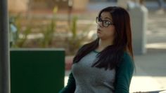 a woman with glasses standing next to a parking meter