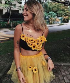 a woman with sunflowers on her crop top and tulle skirt is smiling