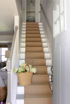 there is a basket with flowers sitting on the stair railing next to the door way